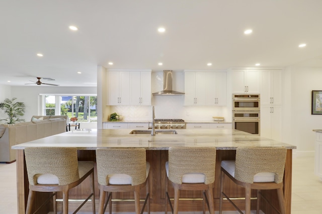 8579 SE Sabal St, Hobe Sound, FL 33455 - kitchen with wall chimney exhaust hood, recessed lighting, a sink, white cabinets, and stainless steel double oven