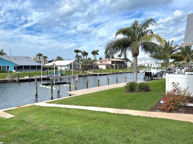 dock area featuring boat lift, a residential view, a yard, and a water view