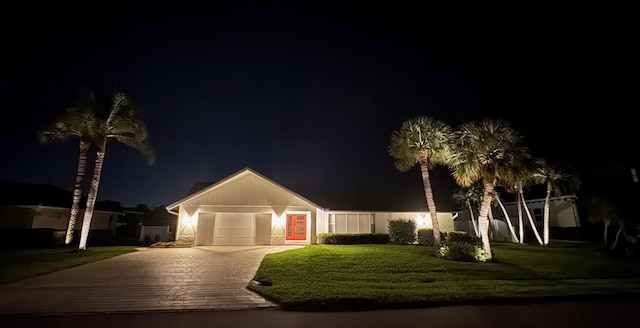 ranch-style home with decorative driveway, an attached garage, and a yard