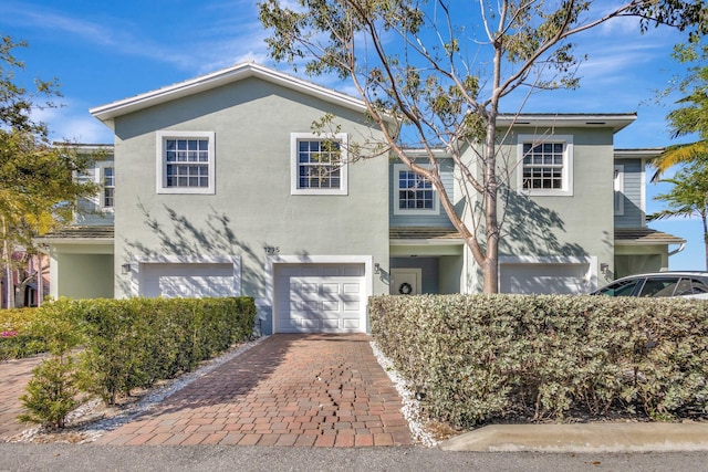 traditional-style home featuring stucco siding, an attached garage, and decorative driveway