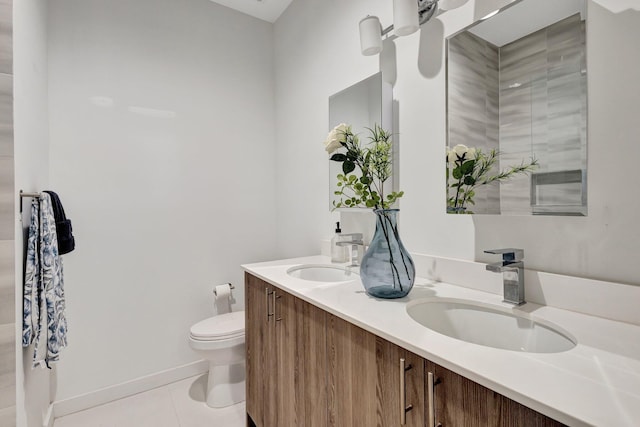 bathroom featuring tile patterned flooring, double vanity, toilet, and a sink