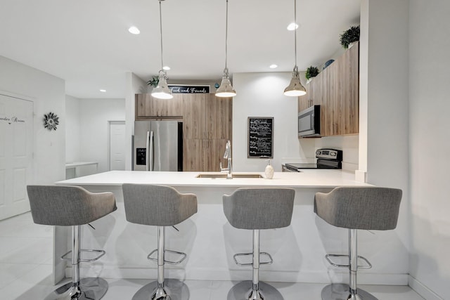 kitchen with a sink, appliances with stainless steel finishes, a peninsula, and a breakfast bar