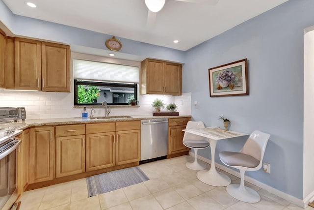 kitchen featuring light stone countertops, a toaster, stainless steel appliances, backsplash, and a sink