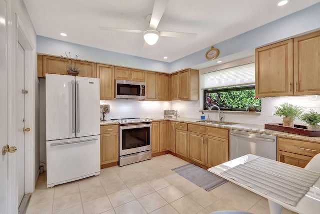 kitchen featuring light stone counters, stainless steel appliances, a sink, a ceiling fan, and backsplash