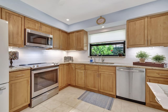 kitchen with tasteful backsplash, appliances with stainless steel finishes, light stone countertops, a sink, and recessed lighting