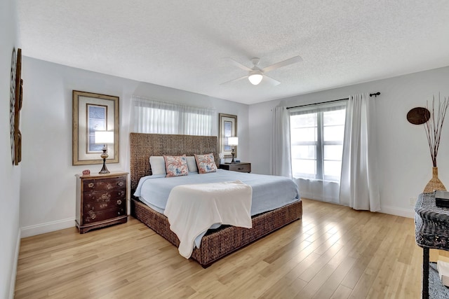 bedroom with light wood-type flooring, ceiling fan, a textured ceiling, and baseboards