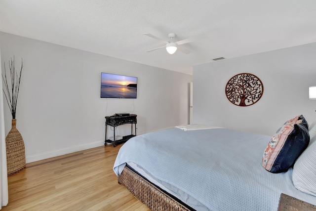 bedroom featuring light wood-style floors, baseboards, visible vents, and ceiling fan