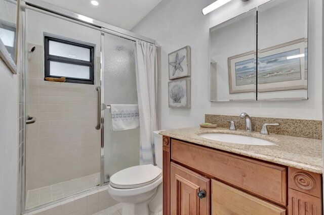 bathroom featuring toilet, a shower stall, and vanity