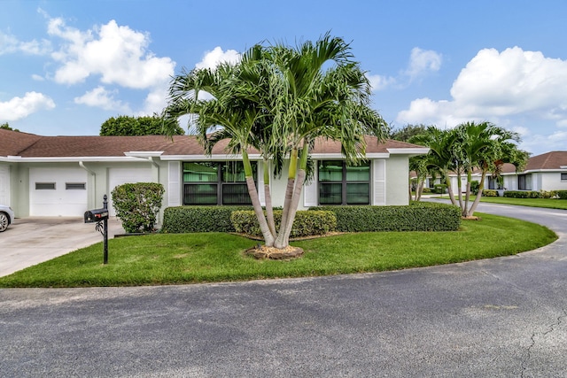 ranch-style house featuring a front lawn, concrete driveway, an attached garage, and stucco siding