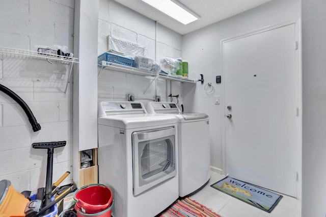 laundry area with laundry area, washing machine and dryer, and concrete block wall