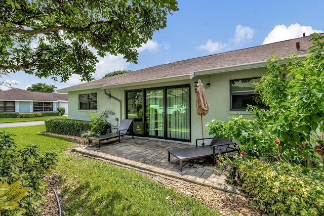 back of house featuring a yard, roof with shingles, a patio area, and stucco siding