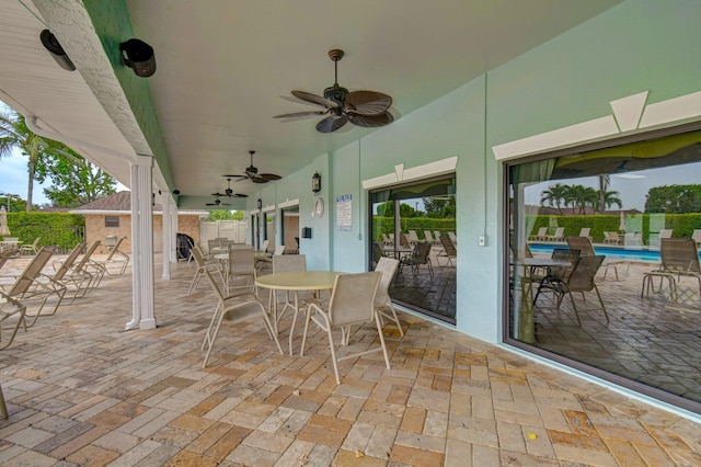 view of patio with a ceiling fan, outdoor dining space, and a community pool