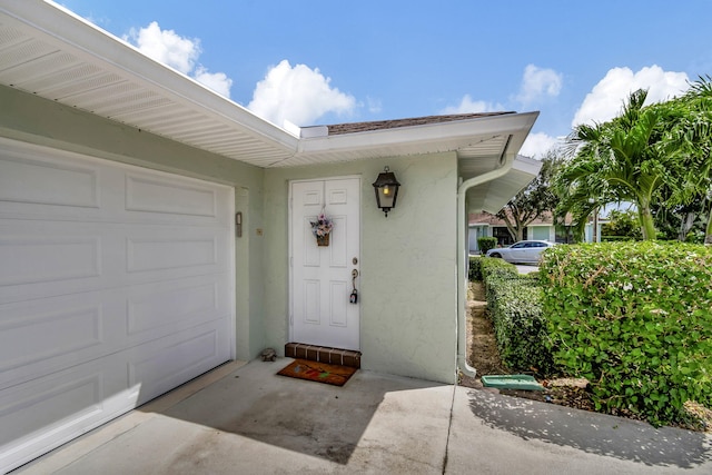 view of exterior entry featuring a garage and stucco siding