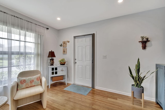 living area featuring baseboards, recessed lighting, and light wood finished floors