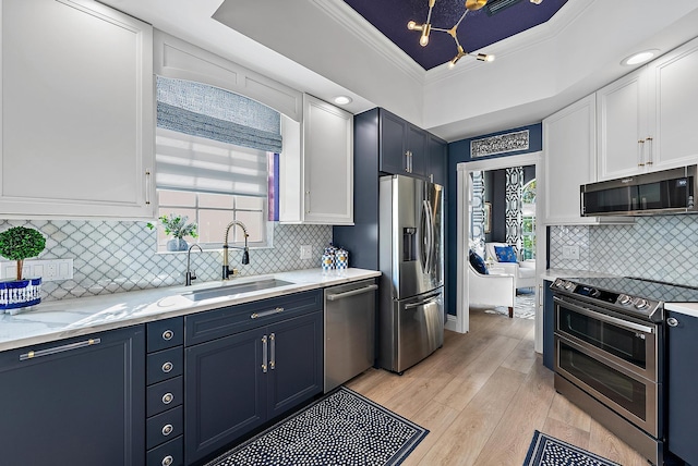 kitchen featuring blue cabinetry, ornamental molding, appliances with stainless steel finishes, white cabinetry, and a sink