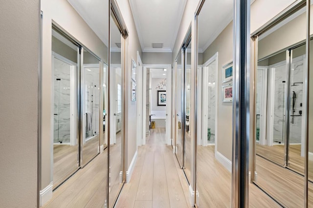 corridor featuring visible vents, baseboards, crown molding, and light wood finished floors