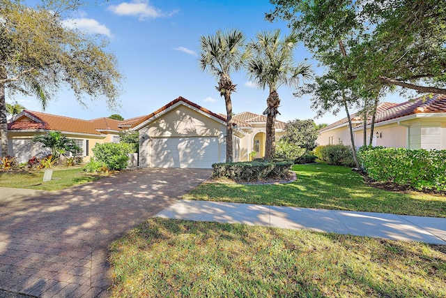 mediterranean / spanish house with a front lawn, a tiled roof, stucco siding, decorative driveway, and an attached garage