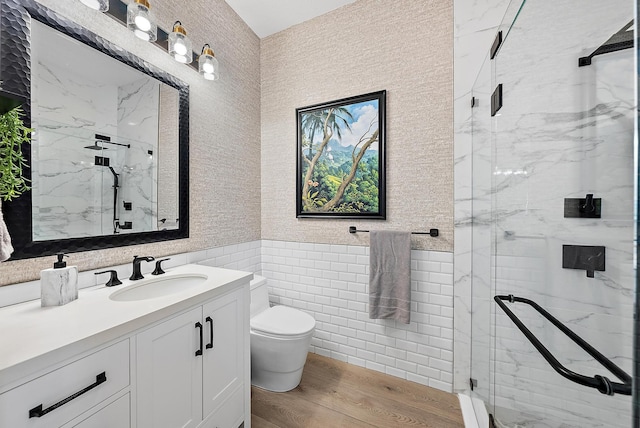 bathroom with tile walls, toilet, wood finished floors, and a marble finish shower