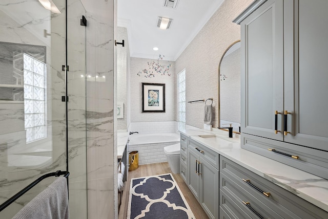 full bathroom featuring vanity, wood finished floors, a marble finish shower, ornamental molding, and a garden tub