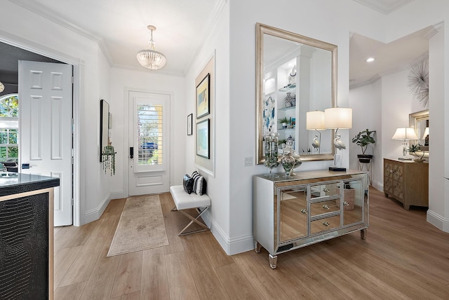 foyer with a notable chandelier, baseboards, light wood-type flooring, and ornamental molding