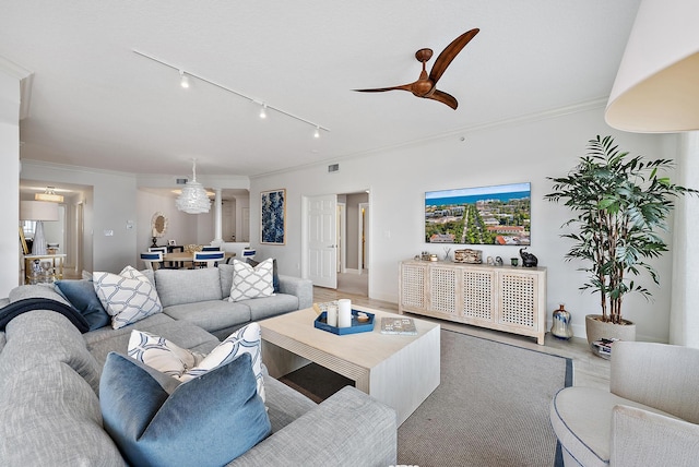 living area featuring light wood-style floors, visible vents, ornamental molding, and a ceiling fan