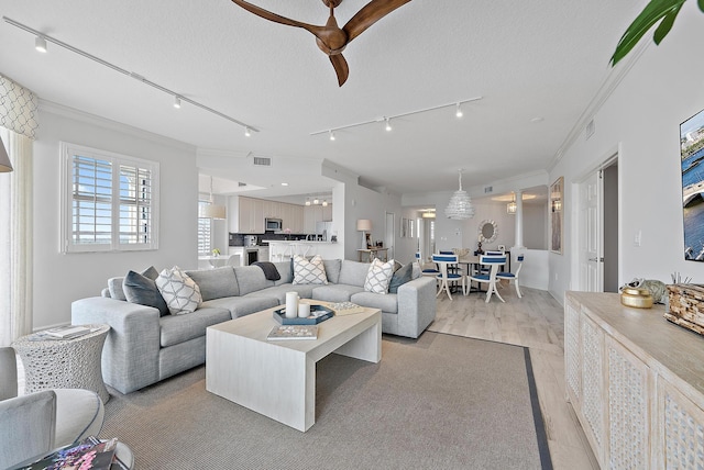 living room with light wood-type flooring, visible vents, crown molding, and a textured ceiling