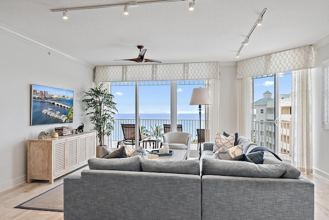 living room featuring a textured ceiling, ceiling fan, wood finished floors, and crown molding