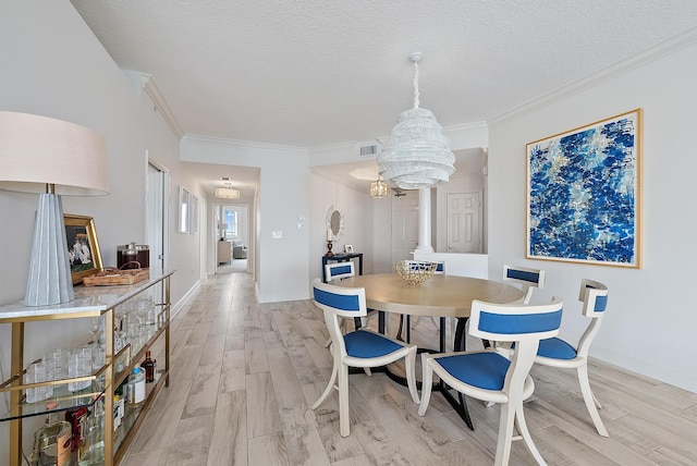 dining area with light wood-style flooring, visible vents, ornamental molding, and a textured ceiling