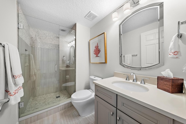 bathroom featuring visible vents, toilet, a textured ceiling, vanity, and a shower stall