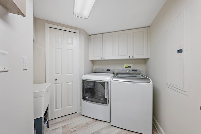 clothes washing area with light wood-style floors, cabinet space, and washing machine and clothes dryer