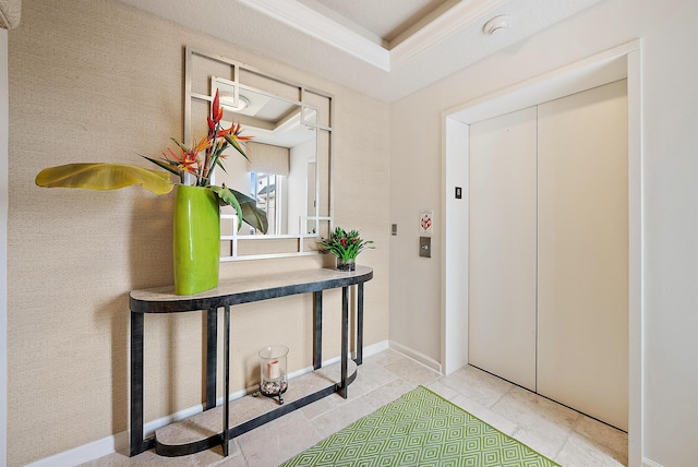 entrance foyer featuring elevator, a raised ceiling, and baseboards