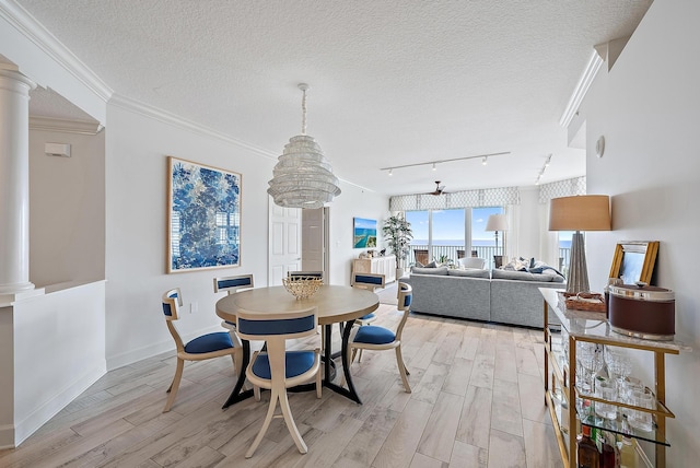 dining room featuring decorative columns, light wood-style flooring, and a textured ceiling