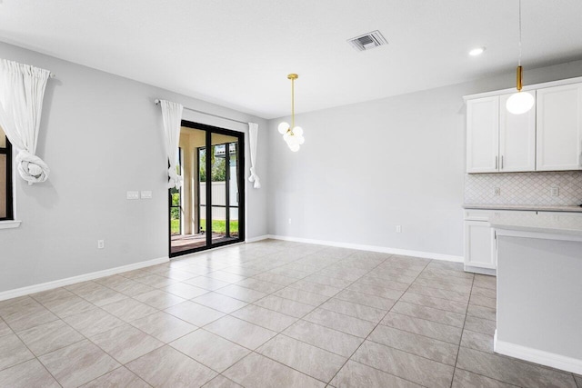 unfurnished dining area with a chandelier, visible vents, baseboards, and light tile patterned floors