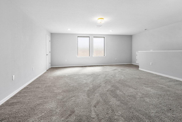 spare room with carpet flooring, visible vents, and baseboards