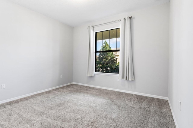 carpeted empty room featuring baseboards