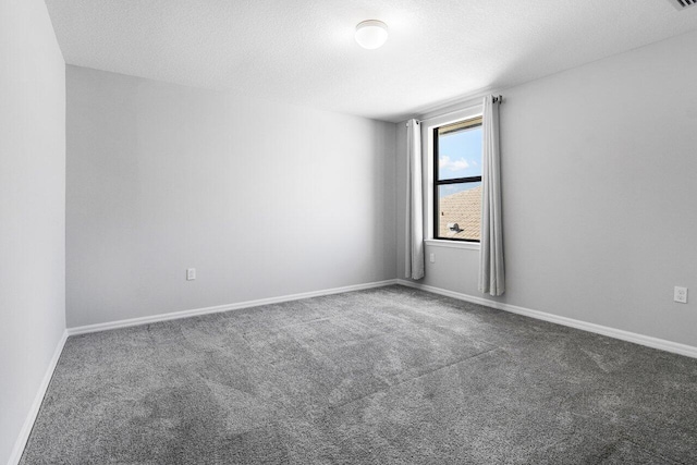 carpeted empty room featuring a textured ceiling and baseboards