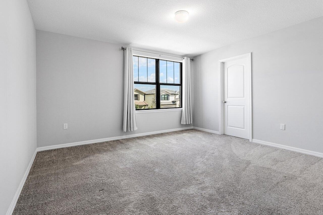 carpeted spare room featuring baseboards and a textured ceiling