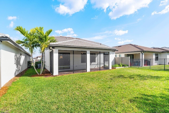 back of house with a fenced backyard, a tile roof, a sunroom, a yard, and stucco siding