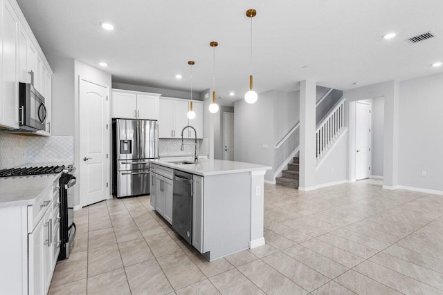 kitchen with visible vents, appliances with stainless steel finishes, decorative light fixtures, light countertops, and a sink