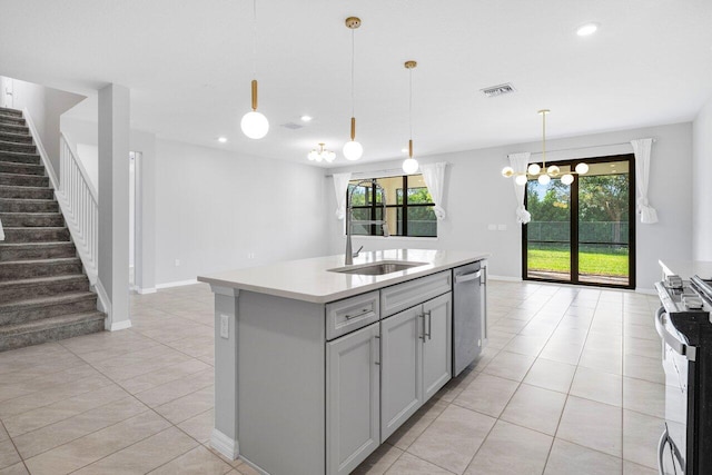 kitchen with visible vents, appliances with stainless steel finishes, a kitchen island with sink, light countertops, and a sink