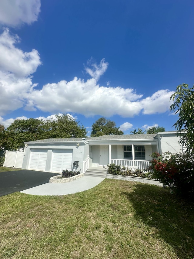 view of front of house with driveway, a garage, covered porch, a front yard, and stucco siding