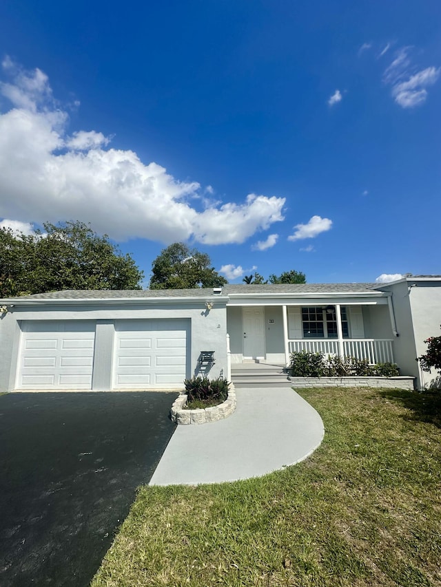 single story home with aphalt driveway, covered porch, a garage, stucco siding, and a front yard