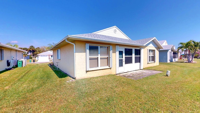 413 European Ln, Fort Pierce, FL 34982 - rear view of house featuring stucco siding, a yard, and roof with shingles
