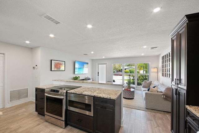 kitchen featuring light wood-type flooring, appliances with stainless steel finishes, visible vents, and open floor plan