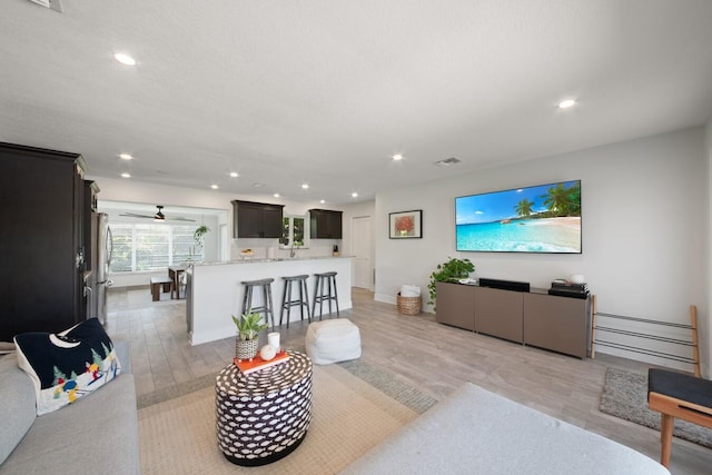 living room with light wood finished floors, visible vents, and recessed lighting