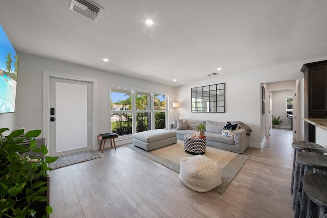 living room with light wood finished floors, baseboards, visible vents, and recessed lighting