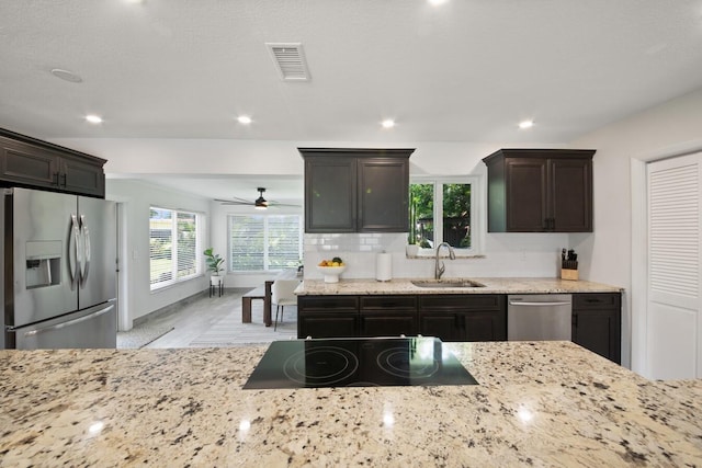 kitchen with light stone counters, appliances with stainless steel finishes, a sink, and visible vents