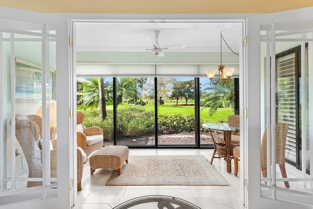 sunroom featuring ceiling fan with notable chandelier