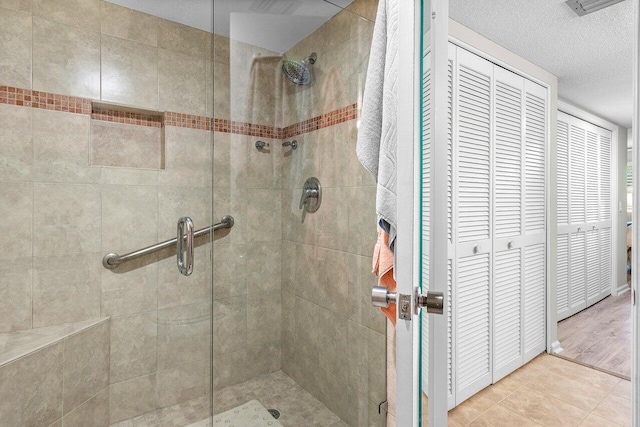 bathroom featuring a shower stall, a textured ceiling, a closet, and tile patterned floors