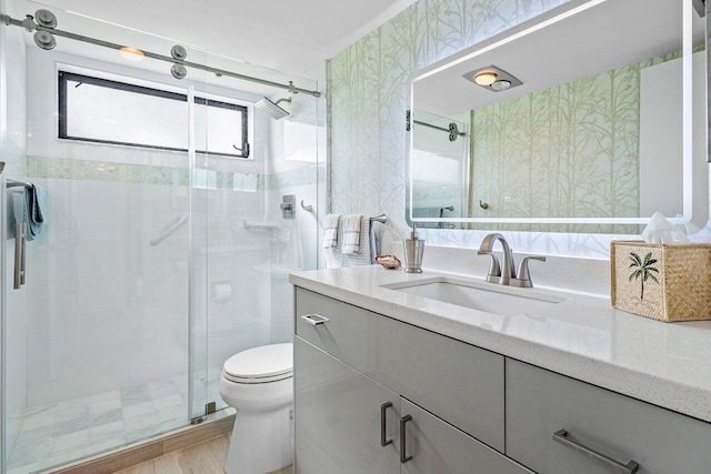 bathroom with a stall shower, vanity, toilet, and wallpapered walls